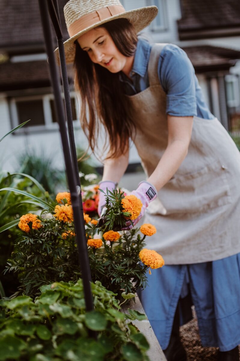 A woman in an apron and hat tending to flowers